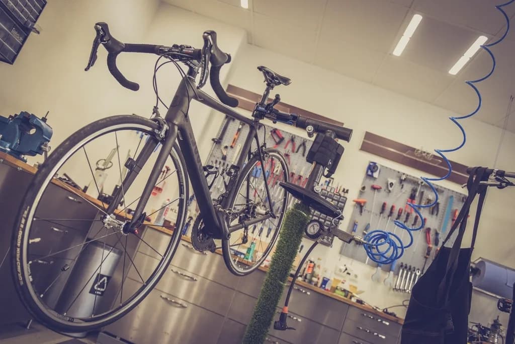 Fahrrad im Montageständer einer Werkstatt, dahinter eine Werkzeugwand und eine Werkbank